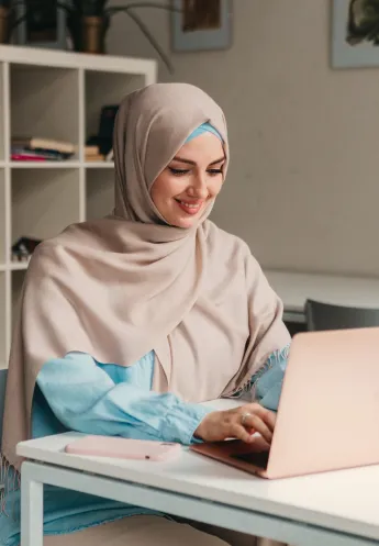 Muslim student learning with a laptop in a bright study space